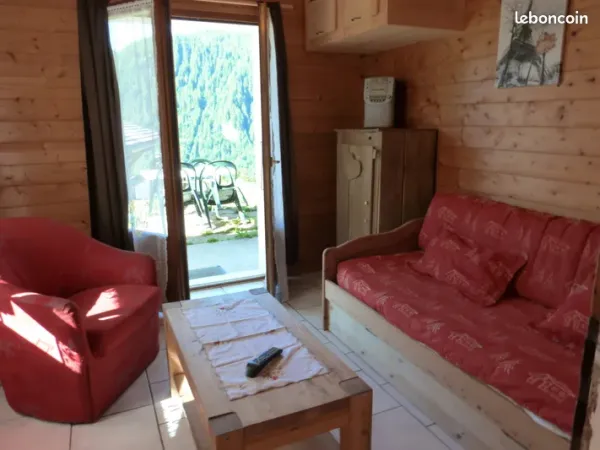 Séjour avec canapé, fauteuil, table basse, porte fenêtre donnant sur la grande terrasse et le jardin