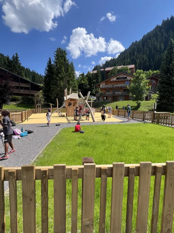 Espace de verdure au premier plan et modules de jeux en arrière plan