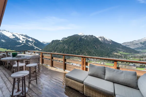 Grande terrasse avec canapé, grande table, vue panoramique sur le village et les montagnes