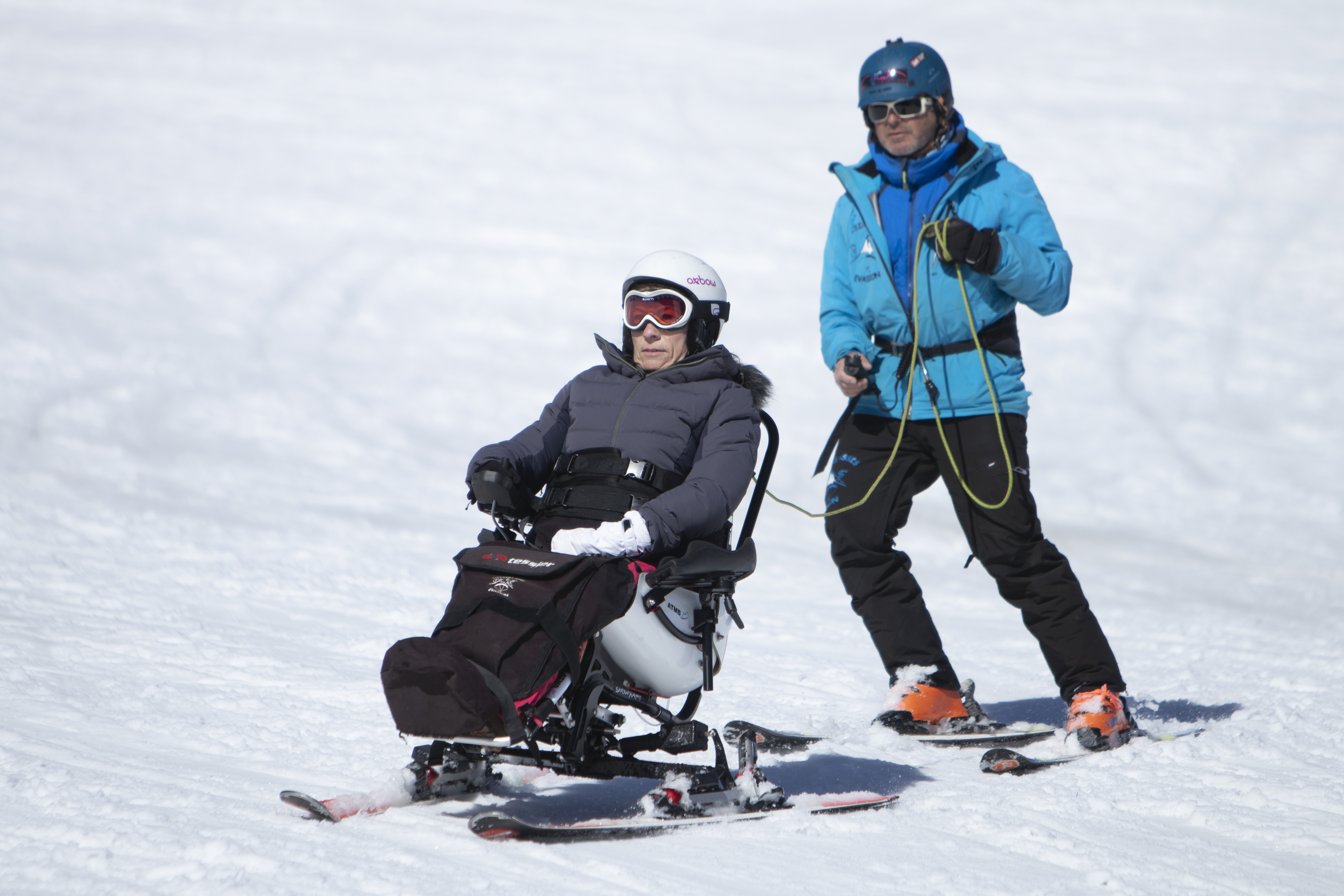Une personne en Tétraski avec un moniteur sur une piste de ski
