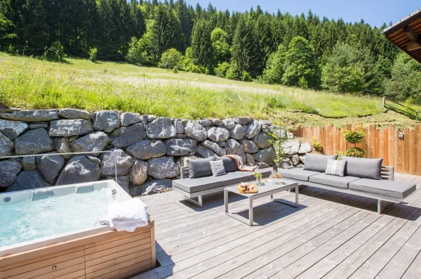 Bain à remous en terrasse l'été avec mobilier de jardin pour profiter de la nature qui l'entoure